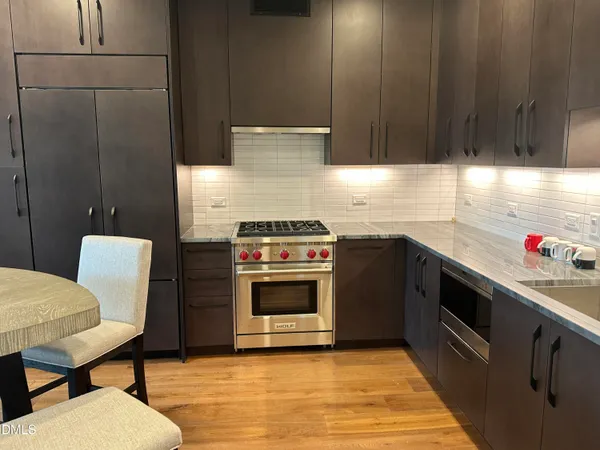 a kitchen with stainless steel appliances a stove a sink refrigerator and a chair