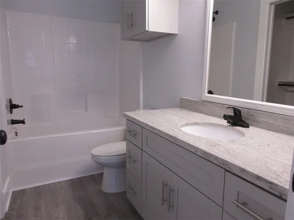 a bathroom with a granite countertop sink a toilet and bathtub