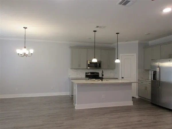 a kitchen with stainless steel appliances granite countertop a sink a stove and a wooden floor