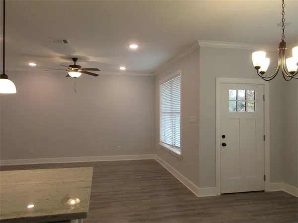a view of an empty room with a window and wooden floor