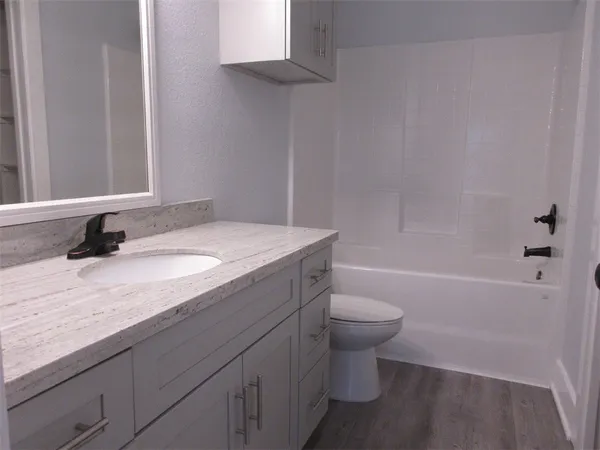 a bathroom with a granite countertop sink a toilet and bathtub