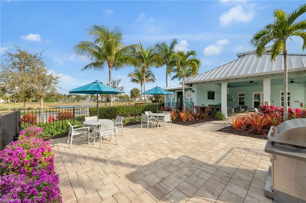4631 Arboretum Circle, Unit 101 Naples, FL 34112 - Photo 21 of 36 a view of a patio with a table and chairs under an umbrella
