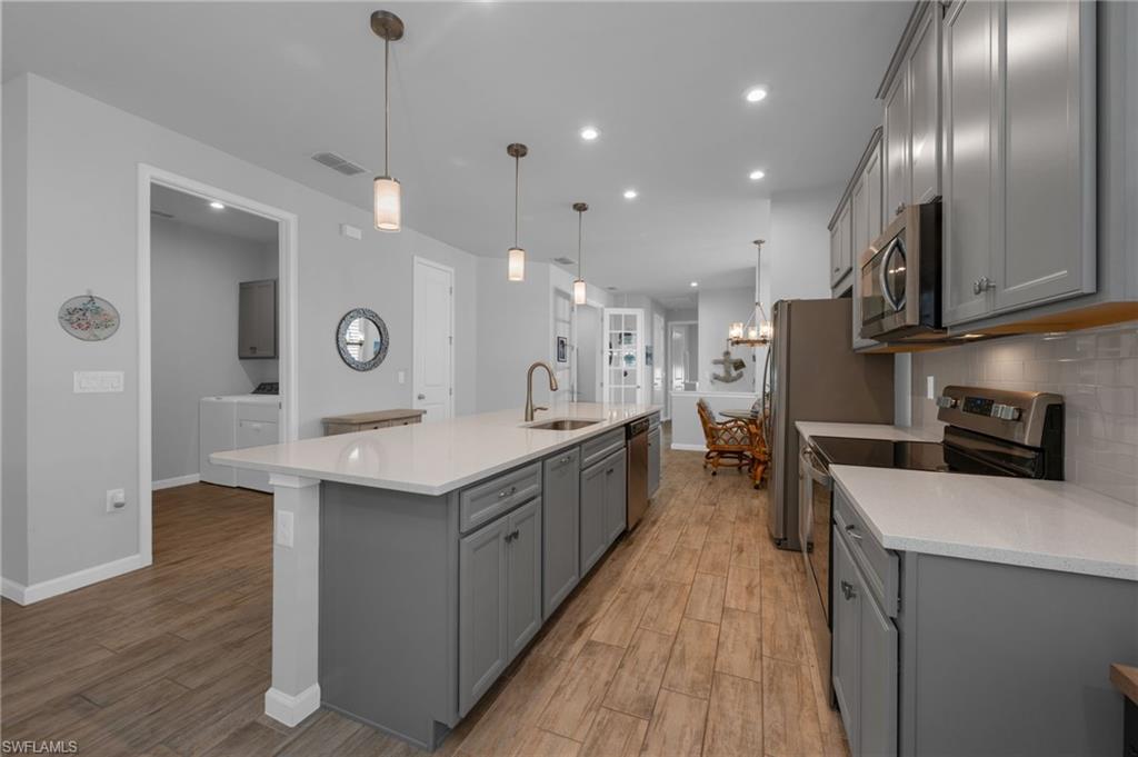 4631 Arboretum Circle, Unit 101 Naples, FL 34112 - Photo 3 of 36 a kitchen with stainless steel appliances granite countertop a sink a stove and a wooden floors