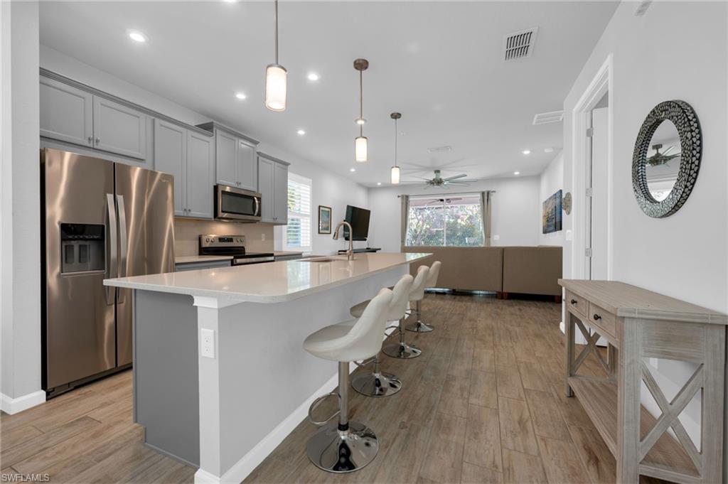 4631 Arboretum Circle, Unit 101 Naples, FL 34112 - Photo 6 of 36 a kitchen with kitchen island wooden floor cabinets and stainless steel appliances