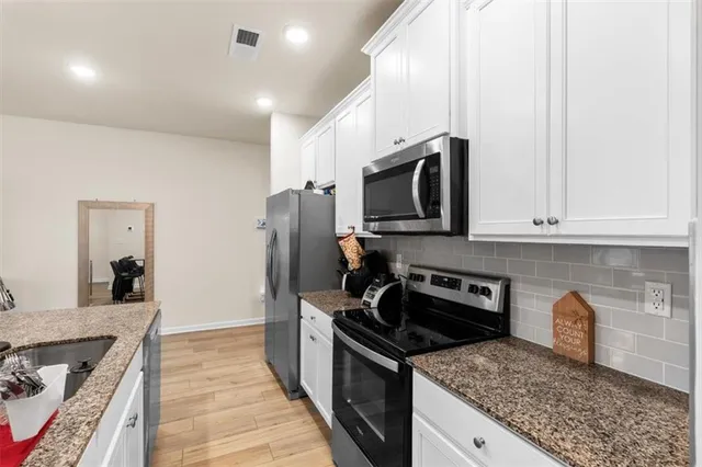 a kitchen with granite countertop a sink a stove and refrigerator