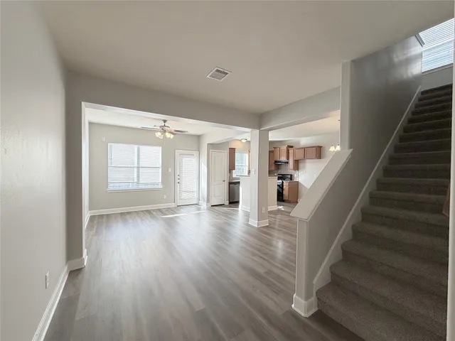 a view of an empty room with wooden floor and stairs