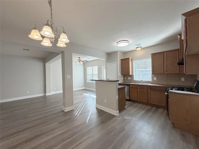 a kitchen with stainless steel appliances granite countertop wooden floors and white cabinets