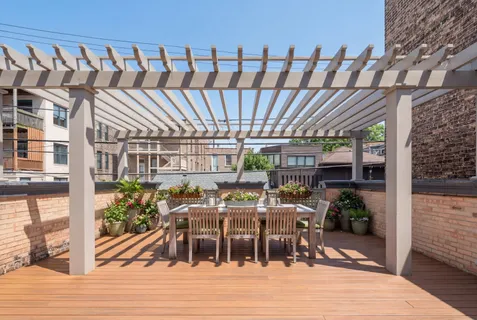 a view of a brick house with plants and large trees