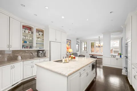a kitchen with a stove a sink and white cabinets with wooden floor