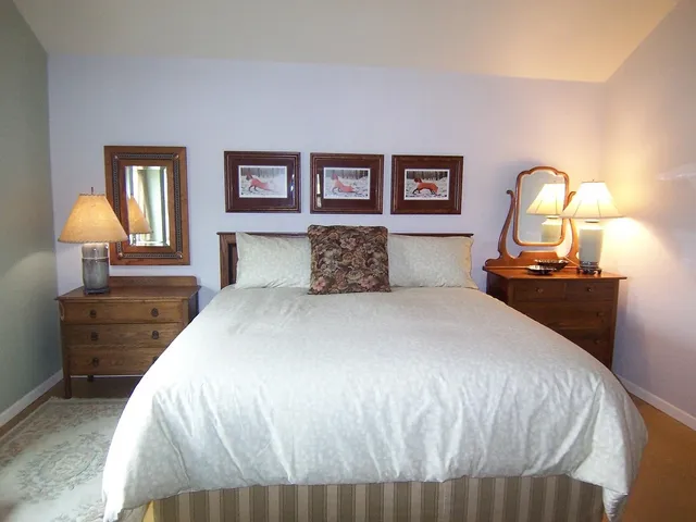 a bedroom with a bed and a lamp on dresser