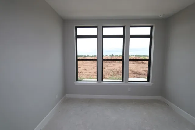 an empty room with chandelier fan and windows