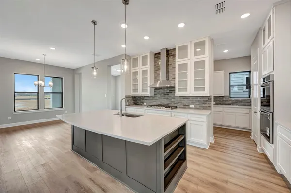 a view of a kitchen with kitchen island a sink stainless steel appliances and a chandelier