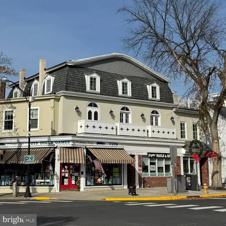 a front view of a building with retail shops and large trees