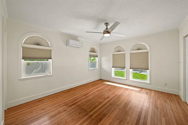 a view of an empty room with a window and wooden floor