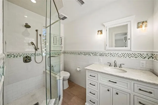a bathroom with a granite countertop sink a toilet and shower