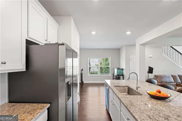 a kitchen with stainless steel appliances granite countertop a refrigerator a sink a stove and a wooden floors