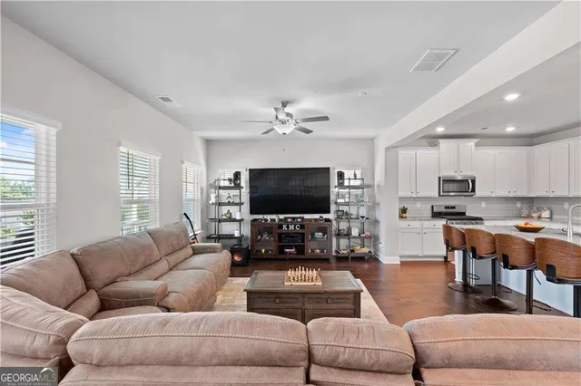 a living room with furniture kitchen view and a flat screen tv