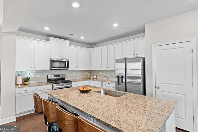 a kitchen with stainless steel appliances granite countertop a sink refrigerator and cabinets
