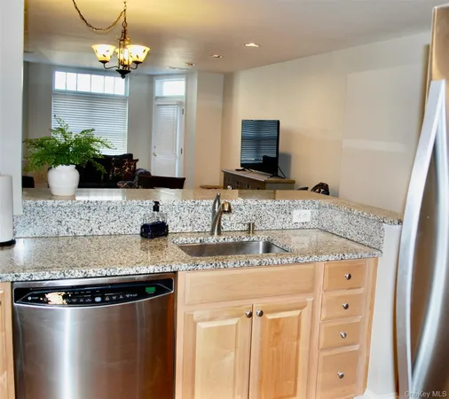 a kitchen with stainless steel appliances granite countertop a sink a microwave a refrigerator and a counter top space