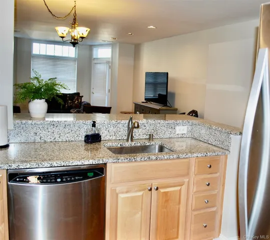 a kitchen with stainless steel appliances granite countertop a sink a microwave a refrigerator and a counter top space
