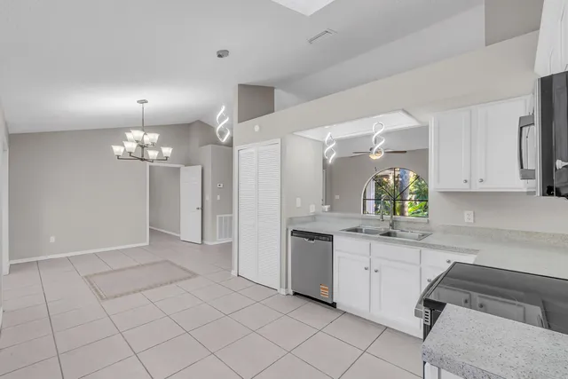 a kitchen with white cabinets and chandelier