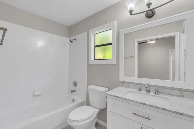 a bathroom with a granite countertop sink toilet a large mirror a bathtub and shower