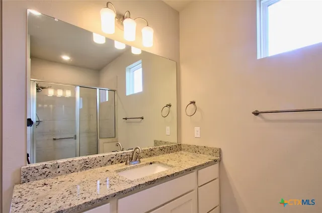 a bathroom with a granite countertop sink a large mirror and a shower