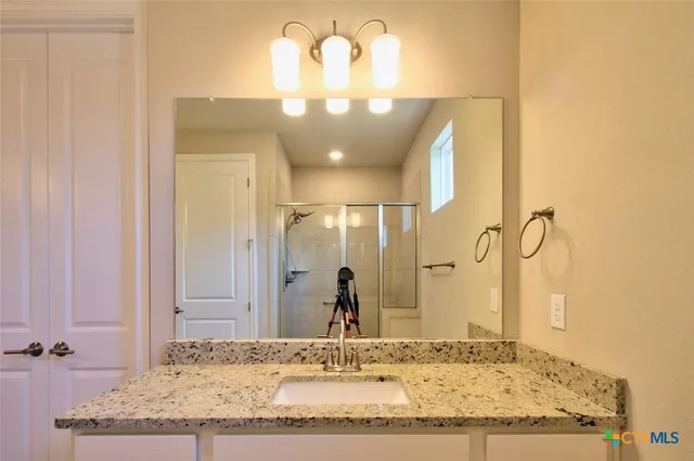 a bathroom with a granite countertop sink and a mirror