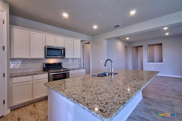 a kitchen with stainless steel appliances granite countertop a sink stove and microwave