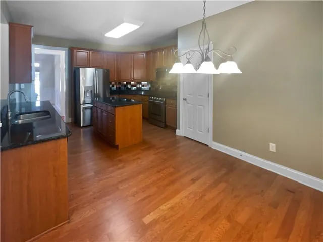 a kitchen with stainless steel appliances kitchen island granite countertop a refrigerator a stove and a sink with granite countertops