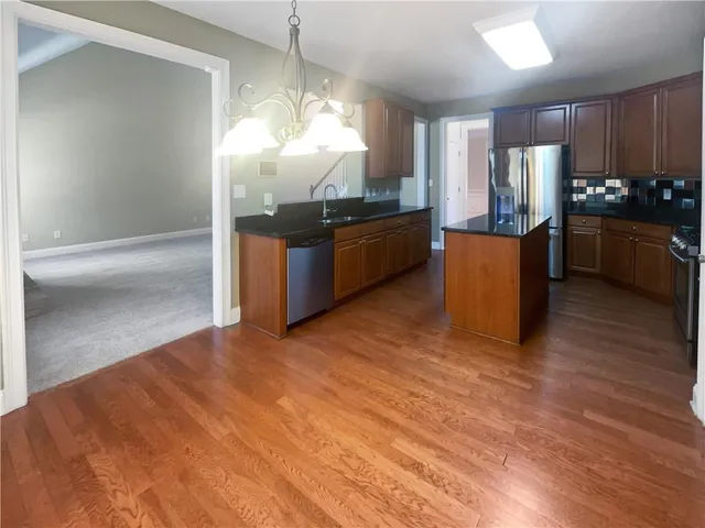 a kitchen with granite countertop a refrigerator and a stove top oven