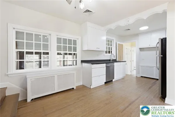 a kitchen with a refrigerator and white cabinets