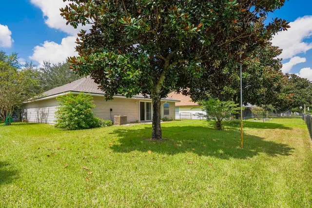 a house is sitting in middle od the grass and trees