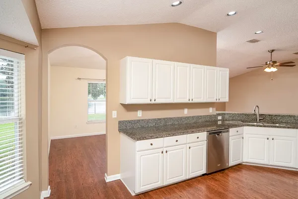 a kitchen with granite countertop a sink cabinets and wooden floor