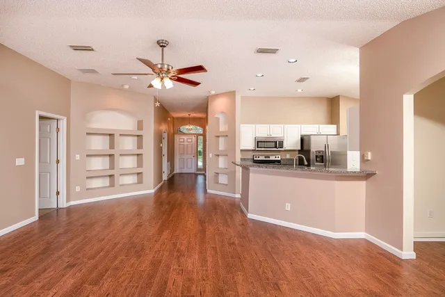 a living room with stainless steel appliances kitchen island hardwood floor and a view of kitchen