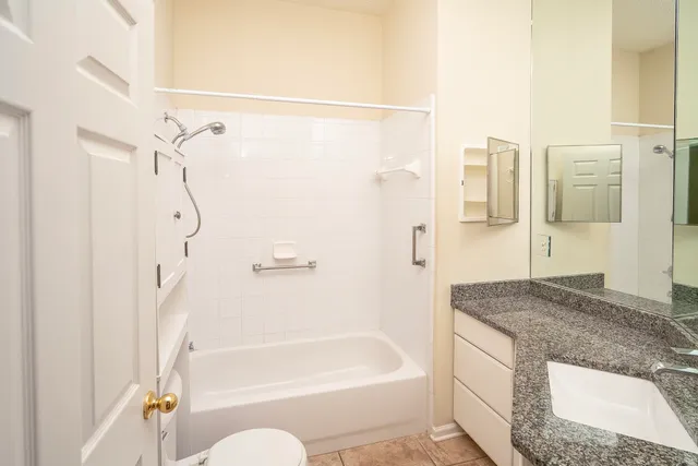 a bathroom with a granite countertop bathtub shower sink and toilet