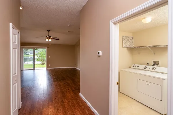 a hallway with wooden floor cabinets and a kitchen