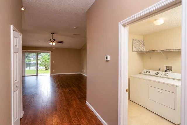 a hallway with wooden floor cabinets and a kitchen