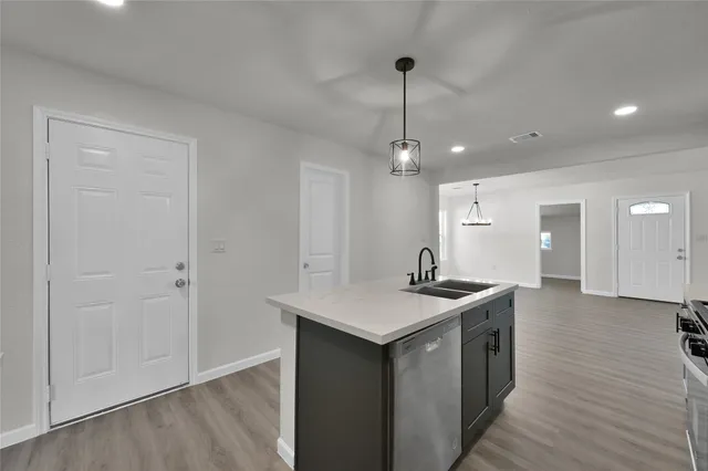 a kitchen with stainless steel appliances granite countertop a sink a stove and a wooden floors