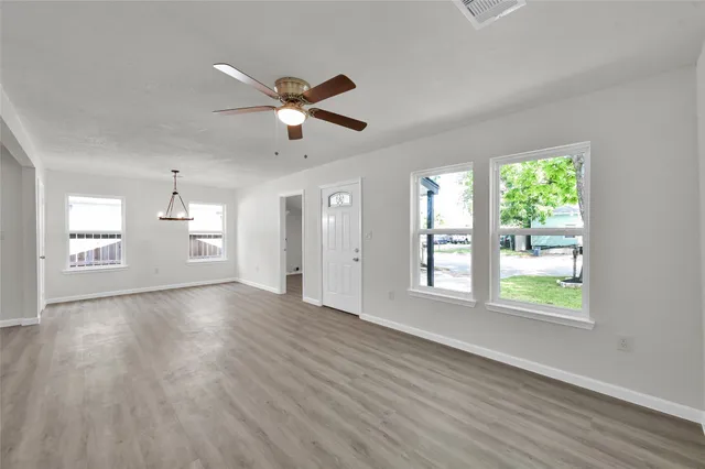 a view of an empty room with a window and wooden floor