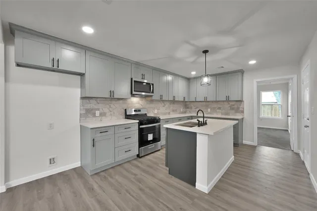 a white kitchen with a sink and dishwasher a refrigerator with wooden floor
