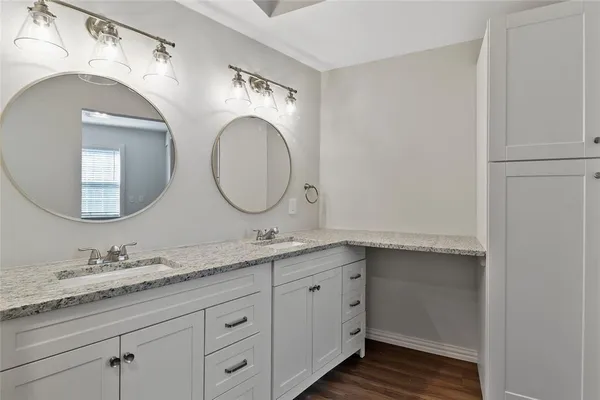 a bathroom with a granite countertop double vanity sink and mirror