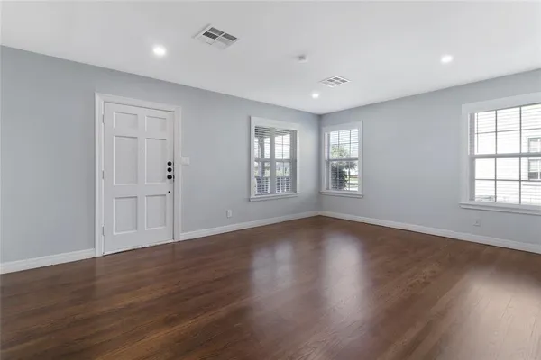 a view of an empty room with wooden floor and window