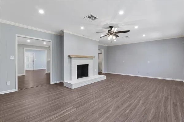 a view of an empty room with wooden floor and a fireplace