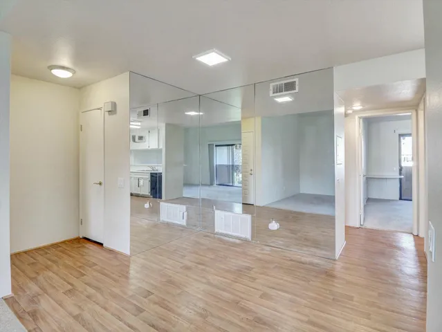 a view of a hallway with wooden floor and a bathroom