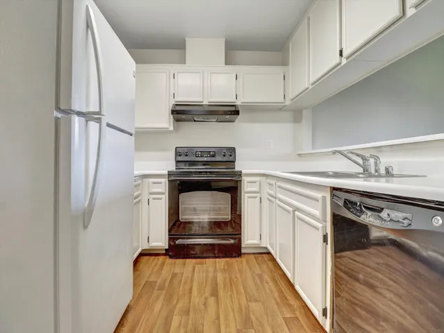 a kitchen with white cabinets and appliances