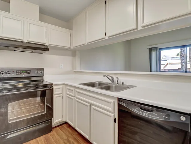 a kitchen with granite countertop a stove sink and cabinets