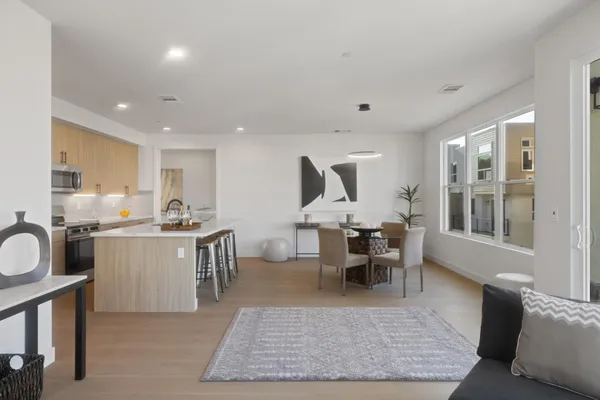 a living room with stainless steel appliances granite countertop furniture wooden floor and a kitchen view