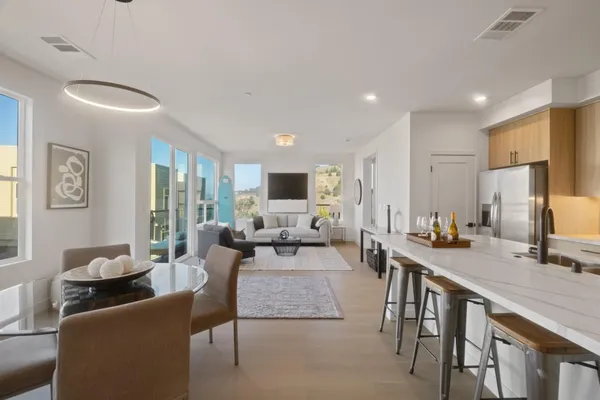 a living room with furniture kitchen view and a large window