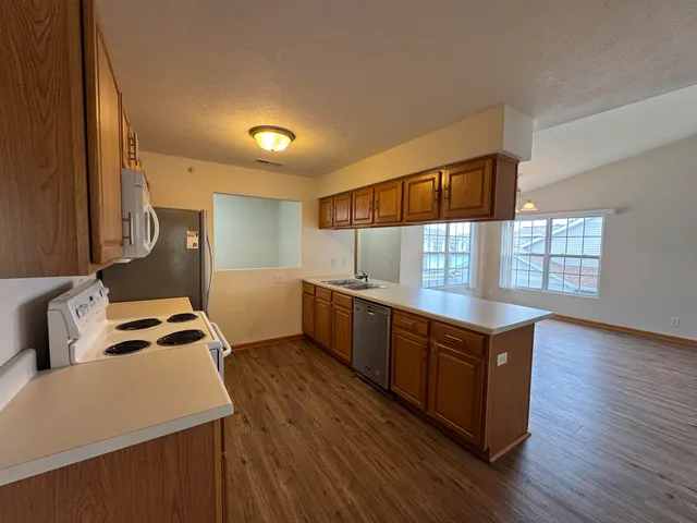 a kitchen with stainless steel appliances granite countertop a sink a stove and wooden floor